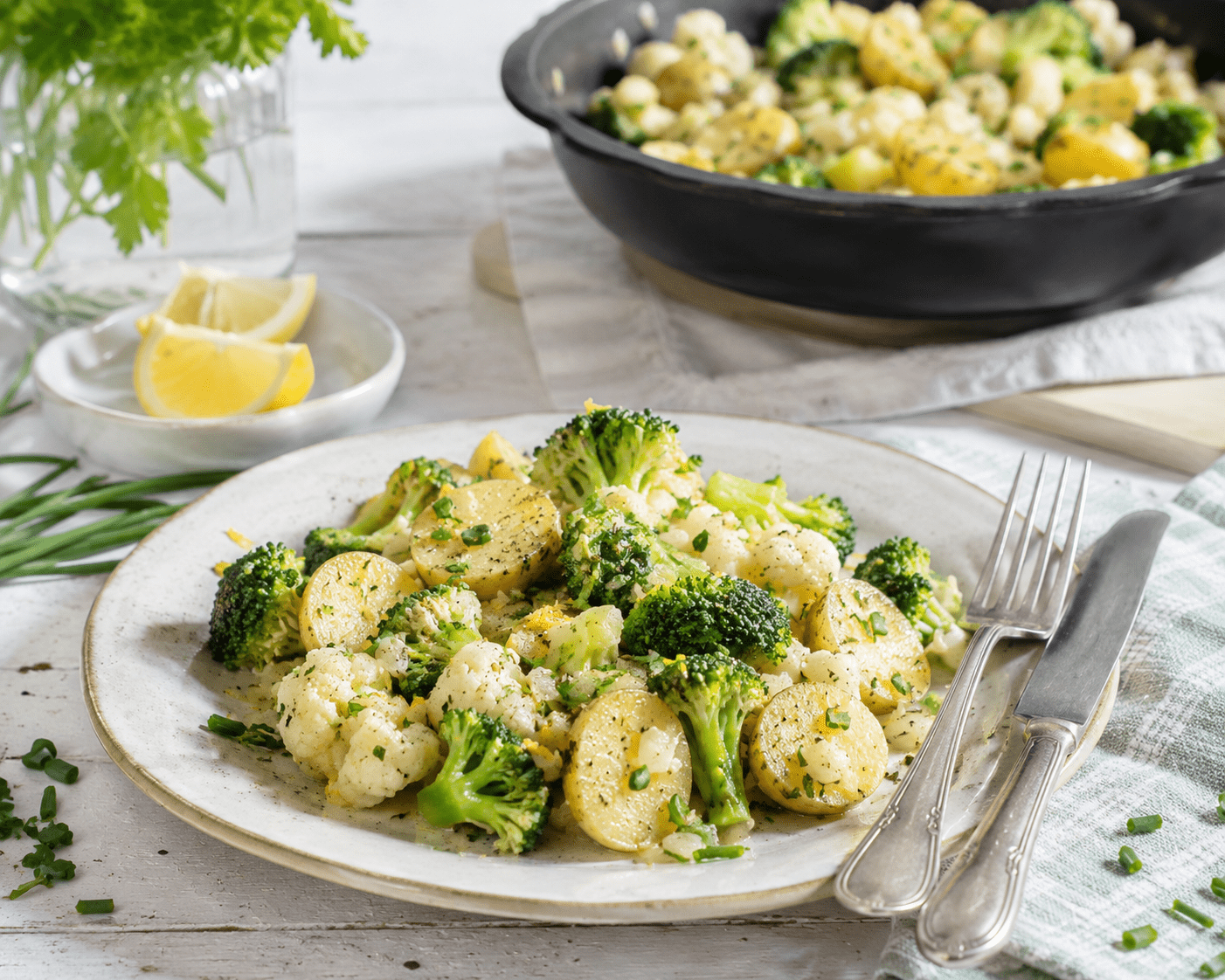 Frühlingspfanne mit neuen Kartoffeln, Brokkoli und Blumenkohl auf einem Teller serviert, mit Kräutern und Zitrone - Rezept vom Obstkorb Neuenkirchen